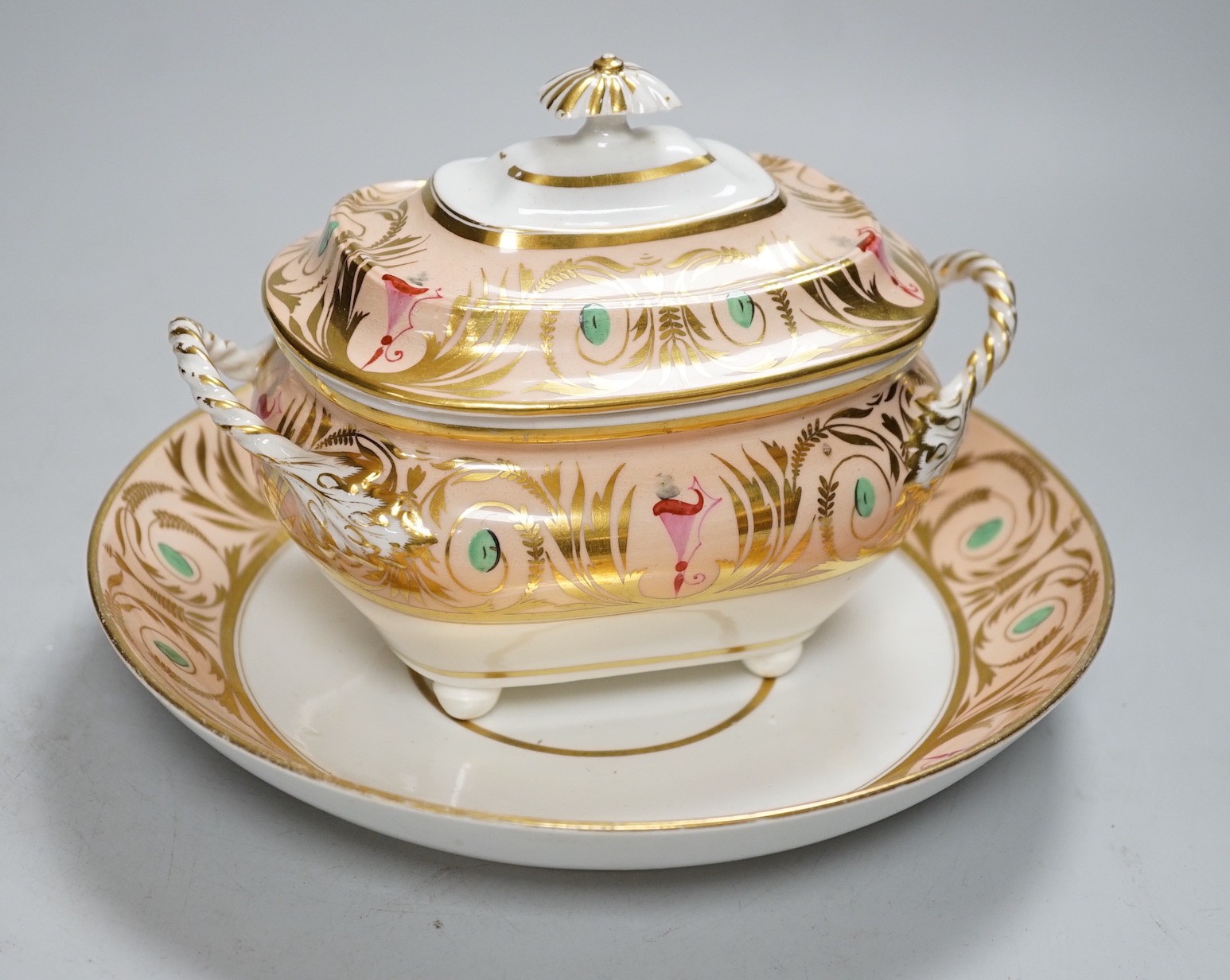 A 19th century Derby sucrier and cover and a matching saucer dish decorated in neo-classical style on a salmon coloured ground, red mark. 15cm tall overall